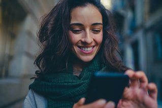 Woman smiling at the phone, showing how easy it is to use the APCOA FLOW app to extend parking. 
